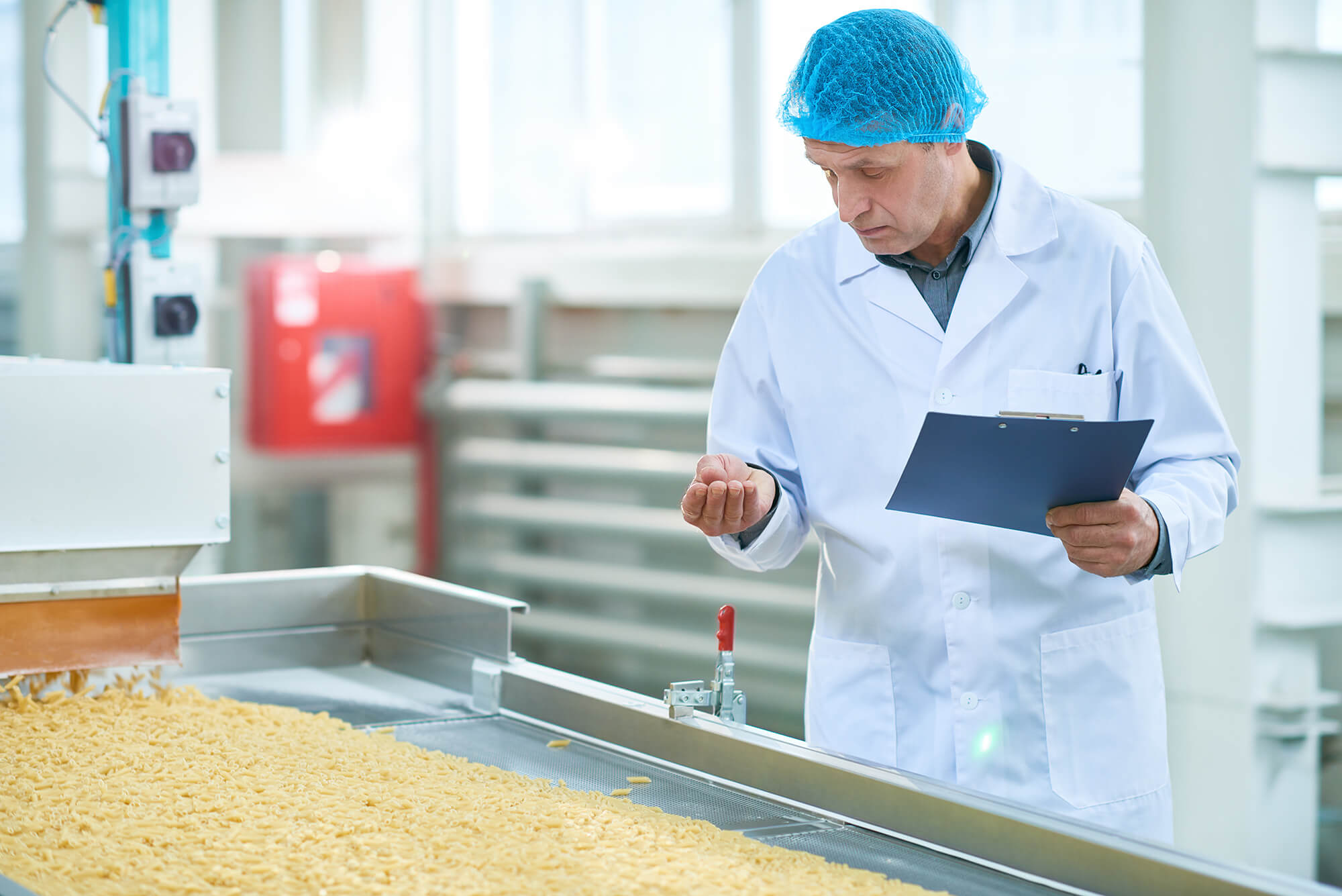 Man with clipboard inspecting food on manufacturing line